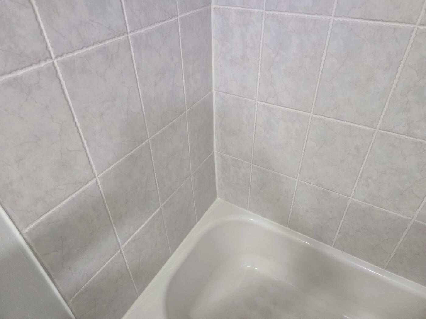 After: clean white grout and silicone in the tub corner
