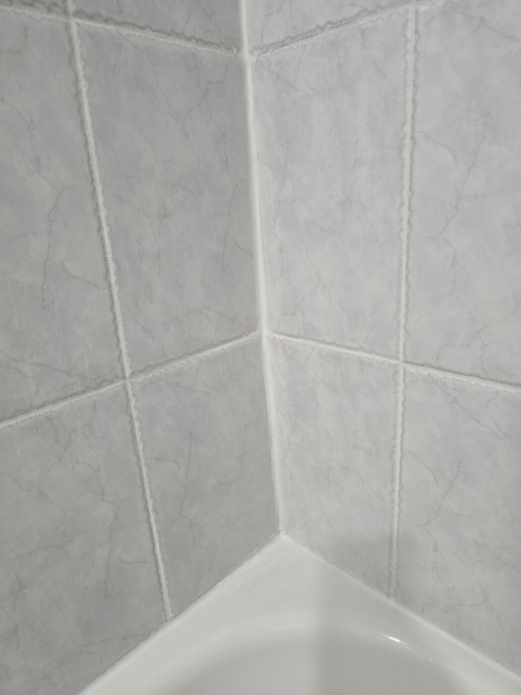 After: fresh grout and a crisp silicone seal in the tub corner
