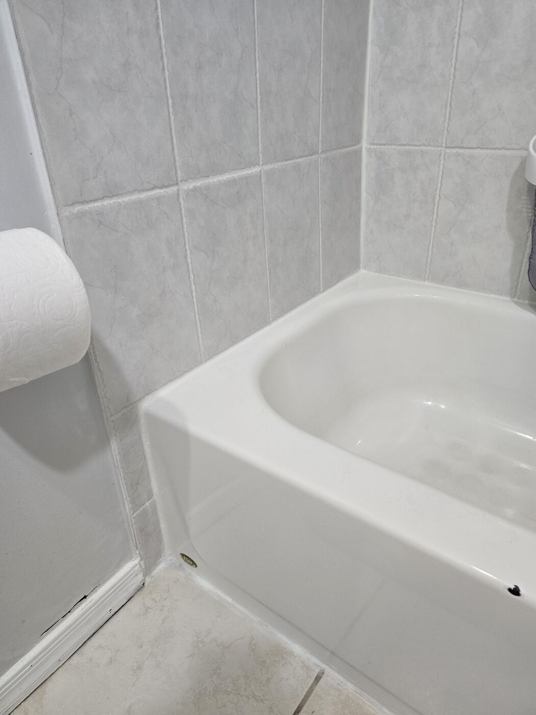 After: fresh white silicone along the tub edge and floor