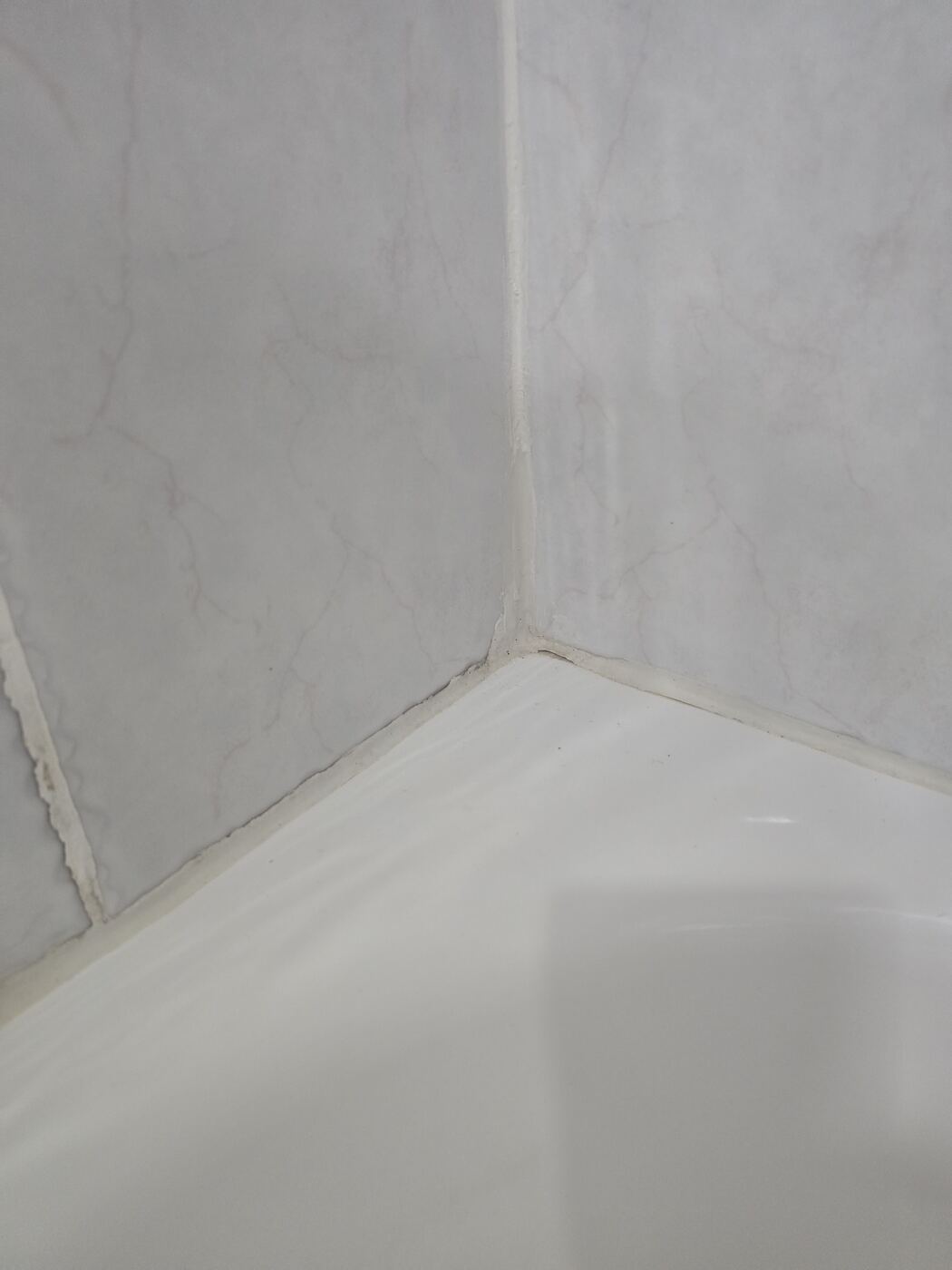 Before: mold-stained caulk along the inside corner above the tub
