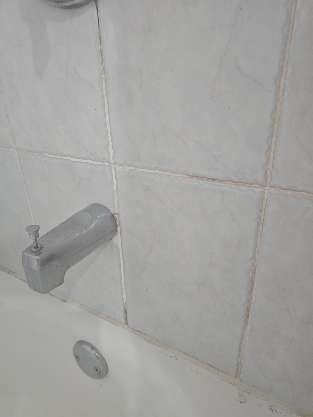 Before: stained, discolored grout around the tub spout