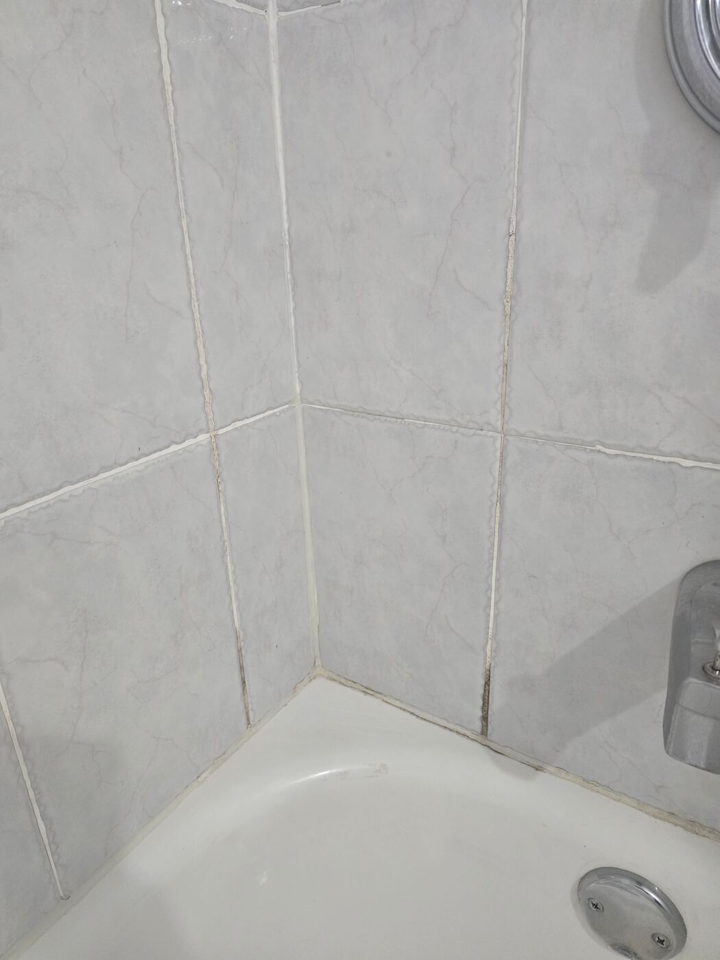 Before: cracked, failing caulk where the tub meets the tile corner